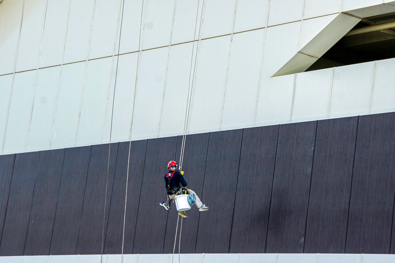Services-02 A window cleaner in safety gear works on a high-rise building facade.