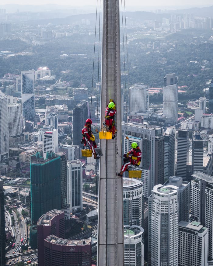 Services-01 Aerial view of workers cleaning skyscraper windows in Kuala Lumpur, Malaysia.